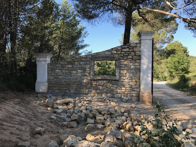 Montage des murs en pierre et piliers avec portail.